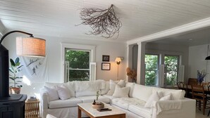 A cozy living room with a white sectional sofa, a wooden coffee table, and a fireplace. - Renovated Catskills Farmhouse - hiking, swimming, quaint towns, 1st floor living (Denver)