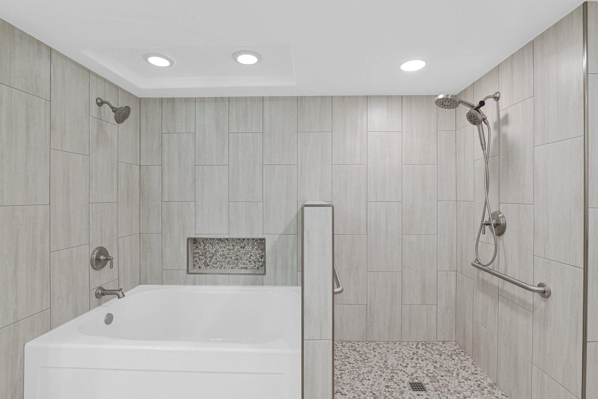 A modern bathroom with a bathtub, shower, and a small decorative tile panel.