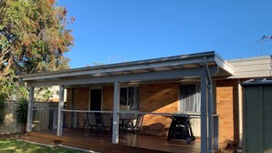 Eine überdachte Terrasse mit Holzdeck, Tisch und Stühlen.