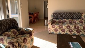 Ein Wohnzimmer mit einer Couch, einem Couchtisch und einem Essbereich im Hintergrund.