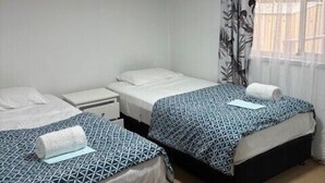 Ein Zimmer mit zwei Betten, einem Deckenventilator und einem Fenster mit Ausblick.
