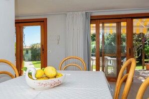 Un comedor con una mesa dispuesta para dos personas, con mantel blanco y un cuenco decorativo con limones.