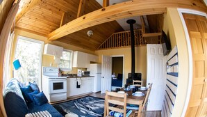Un intérieur de chalet chaleureux comprenant un espace de vie, une cuisine et un coin repas.