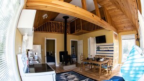 Un intérieur de chalet chaleureux comprenant une cuisine, un coin repas et une chambre à coucher située en mezzanine.