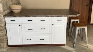 A kitchen with a granite countertop, white cabinetry, and a stone accent wall. - Hamilton Goebel House 816 E Louisa St Darlington Wi  (Darlington)