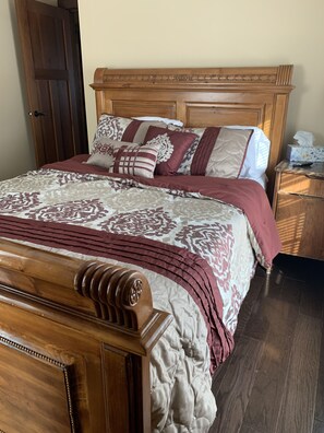 Una cama bien hecha con cabecera de madera y colcha estampada.