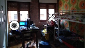 Una habitación con escritorio, computadora, literas y ventana con persianas.