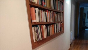 Un pasillo con piso de madera y una estantería llena de libros.