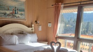 Une chambre avec un grand lit, un tableau accroché au mur et une vue sur l’extérieur par une fenêtre.