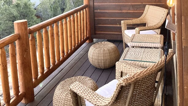 A wooden deck with wicker chairs and a lantern.