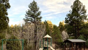 A playground with a slide, swings, and a small shelter.