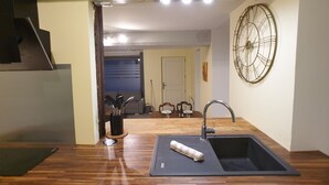 A kitchen with a wooden countertop, a sink, and a wall-mounted clock.