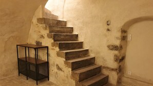 A staircase with stone steps leading to a landing, a metal table, and a wall with a small door.