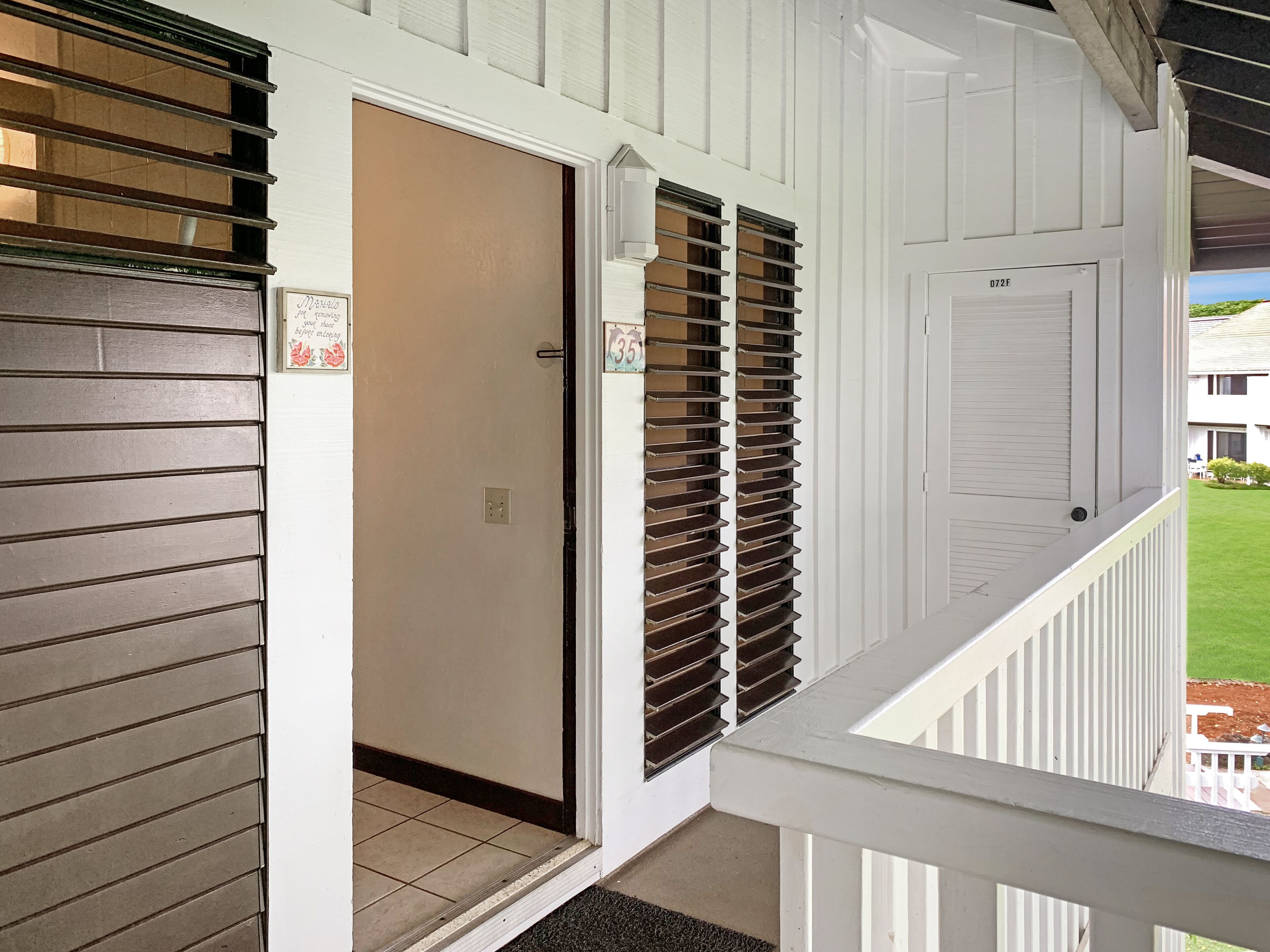 A white exterior with a closed door, a window with blinds, and a balcony railing.