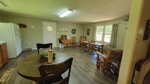 Un comedor con mesa y sillas de madera, un refrigerador y una ventana con cortinas.