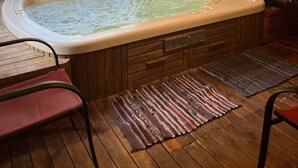 L'intérieur d'un chalet en bois, avec un jacuzzi, une fenêtre donnant sur un paysage verdoyant et un tableau accroché au mur.