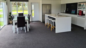 Una cucina moderna con isola centrale, mobili bianchi e zona pranzo con tavolo e sedie.