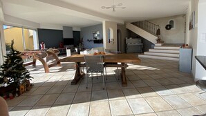 A spacious living area with a dining table, sofas, a TV, and a staircase leading to an upper floor. - Villa Avec VUE Exceptionnelle Dans UN Ecrin DE Verdure (Cagnes-sur-Mer)
