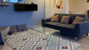 A living room with a glass coffee table, a blue sofa, and a patterned rug. - Villa Avec VUE Exceptionnelle Dans UN Ecrin DE Verdure (Cagnes-sur-Mer)