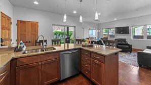 Una cocina moderna con armarios de madera, lavavajillas de acero inoxidable e iluminación colgante.