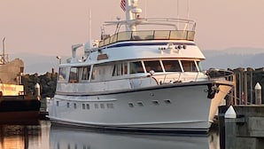 A white yacht docked at a marina with a clear view of the surrounding area.