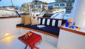 A cozy seating area with a cushioned bench, a small table with a red cloth, and a bowl of fruit. - Don't book a place, book an Alaskan Adventure on an 85 foot Super Yacht (Ketchikan)
