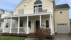 A two-story house with a front porch, a garage, and a small front yard. - Best location on the island (Brigantine)