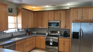 A kitchen with wooden cabinets, stainless steel appliances, and a tiled floor. - Best location on the island (Brigantine)