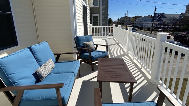 A covered outdoor seating area with a sofa, chairs, and a table. - Best location on the island (Brigantine)