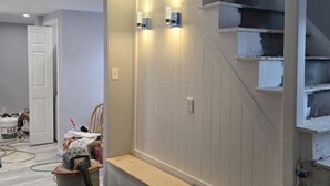 Ett rum som är under renovering, med synliga väggar, en träbänk och en trappa.