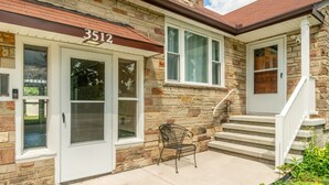 A stone building with a number '3512' above the entrance, a front door, a bench, and a set of stairs leading to a porch. - Parkside Estate, Niagara Falls, USA + Free Parking (Niagara Falls)