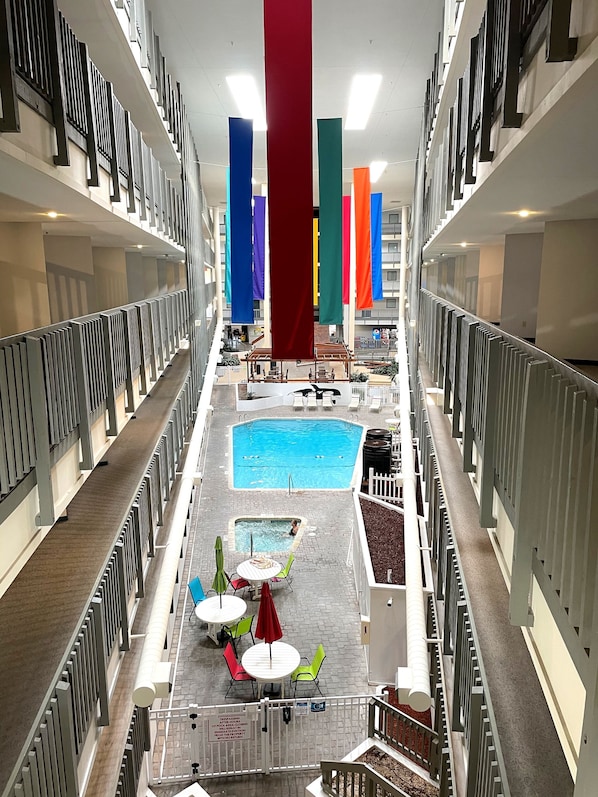 A multi-level indoor swimming pool area with a central pool, smaller pools, and seating areas.