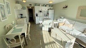 Un espacio habitable compacto con comedor, sofá, una mesita y una kitchenette.