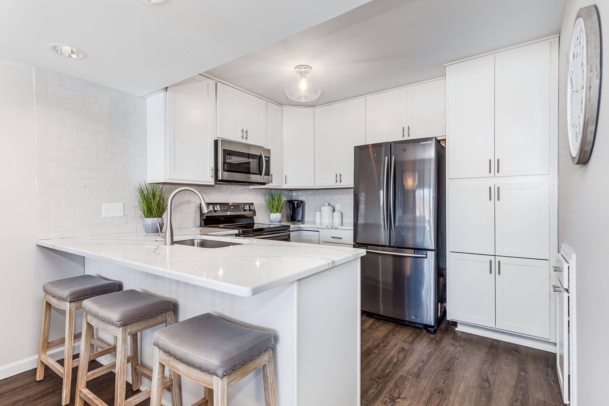 A modern kitchen with white cabinets, stainless steel appliances, and a central island with bar stools.
