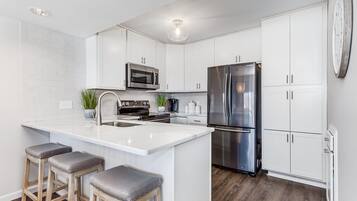 A modern kitchen with white cabinets, stainless steel appliances, and a central island with bar stools.