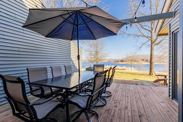 A deck with a table and chairs, a large umbrella, and a view of a lake. - Gorgeous, Completely Remodeled, Waterfront Condo on Aspen Lake! (Innsbrook)