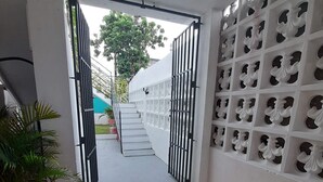 Un couloir doté d’un sol carrelé, une porte-grille donnant sur l’extérieur et un mur orné de motifs découpés.