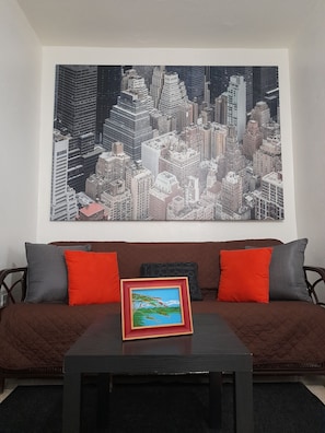 Relax in this stylish living room with a large cityscape painting and comfortable seating area.