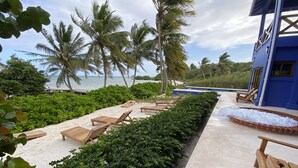 Ein Strandresort mit Liegestühlen, einem Swimmingpool und Palmen.