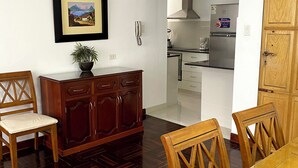 A dining area with a wooden table and chairs, a wooden cabinet, and a framed picture on the wall. - Bright 2BR Apartment Steps from El Olivar Park (San Isidro)