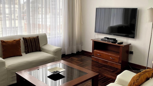 A modern living room with a sofa set, a coffee table, a flat-screen TV, and a wooden cabinet. - Bright 2BR Apartment Steps from El Olivar Park (San Isidro)