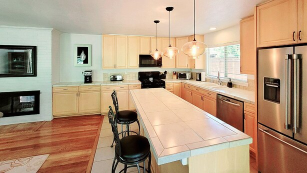 Une cuisine moderne avec des meubles en bois, des appareils électroménagers en acier inoxydable et des luminaires suspendus.