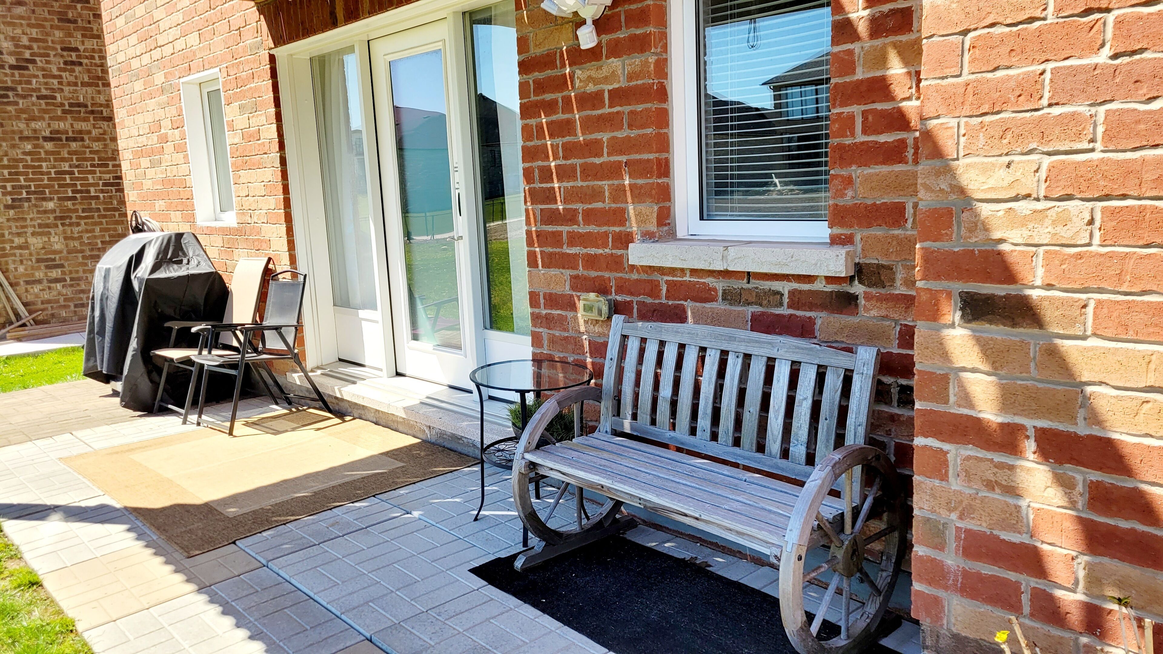 A patio with a bench, a table, and a grill.