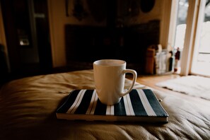 Une tasse blanche posée sur un sous-verre rayé, sur un lit.