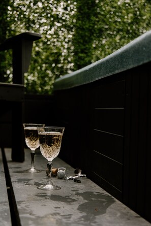 Un banc avec deux verres d’eau et un bouchon de bouteille posés sur une surface mouillée.