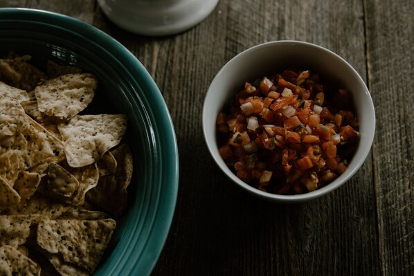 Un bol de chips de tortillas et un bol de salsa sur une table en bois.