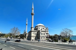 Ein großes Gebäude mit einer markanten Kuppel und zwei hohen Minaretten an einer Uferpromenade.