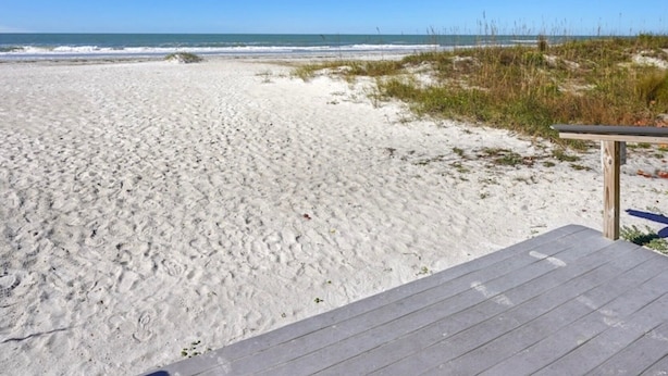 A beach with a wooden deck and sand dunes in the background.