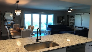 A modern kitchen with granite countertops, a stainless steel sink, and a dining area with a table and chairs.