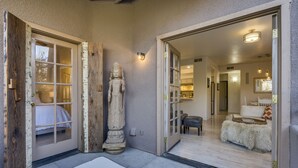 A modern interior with a large statue, a white bench, and a well-lit hallway leading to a living area.